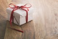 White paper gift box with thin red ribbon bow on old wood table with copy space Royalty Free Stock Photo