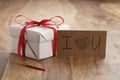 White paper gift box with thin red ribbon bow on old wood table Royalty Free Stock Photo