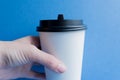 White paper kraft disposable cup for coffee with black plastic lid. coffe to go on blue background Royalty Free Stock Photo