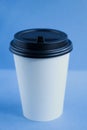 White paper kraft disposable cup for coffee with black plastic lid. coffe to go on blue background Royalty Free Stock Photo