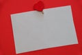 White paper note with pin with red heart on red background close-up top view, flat composition with empty space for Royalty Free Stock Photo