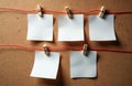 White paper notes pinned with clothespins on red string against cork texture. Blank spaces for writing messages, planning, or Royalty Free Stock Photo