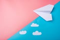 White paper origami airplane with clouds lies on pastel blue background Royalty Free Stock Photo