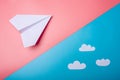 White paper origami airplane with clouds lies on pastel blue background Royalty Free Stock Photo