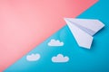 White paper origami airplane with clouds lies on pastel blue background Royalty Free Stock Photo