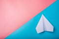 White paper origami airplane lies on pastel colors background Royalty Free Stock Photo