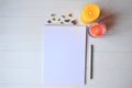 White paper and pencil with decoration on the white wooden desk, top view.