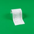 A white paper receipt with printed text in black ink is shown against a solid green Royalty Free Stock Photo