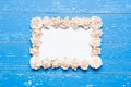 White paper sheet with frame made of roses on blue Royalty Free Stock Photo