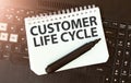 White paper sheet with text CUSTOMER LIFE CYCLE on the black laptop Royalty Free Stock Photo