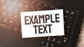 White paper sheet with text EXAMPLE TEXT on the black laptop Royalty Free Stock Photo