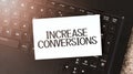 White paper sheet with text increase conversions on the black laptop