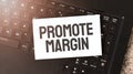 White paper sheet with text PROMOTE MARGIN on the black laptop Royalty Free Stock Photo