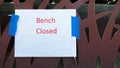 A white paper sign saying `Bench Closed` due to lockdown, with copy space