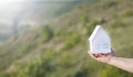 White paper small house in a womanÃ¢â¬â¢s hand. Defocused background Royalty Free Stock Photo