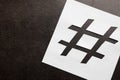 White paper stencil with symbol of hashtag on dark background, top view. Space for text