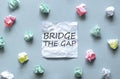 White paper with text Bridge The Gap on the blue background with a lot of another paper Royalty Free Stock Photo
