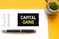 White paper with text CAPITAL GAINS in male hands on a white background