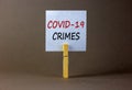 White paper with text `covid-19 crimes`, clip on wood clothespin. Beautiful grey background. Covid-19 pandemic concept. Copy spa