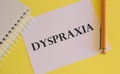 White paper with text Dyspraxia , difficulties with physical movement and memory, dyspraxia concept, random letters around, white