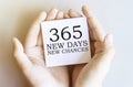 White paper with text 365 New Days New Chances in male hands on a white background