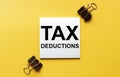 White paper with text Tax Deductions on a yellow background with stationery