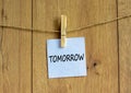 White paper with text `tomorrow`, clip on wood clothespin. Beautiful wooden background. Business concept. Copy space Royalty Free Stock Photo