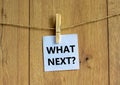White paper with text `Whats next`, clip on wood clothespin. Beautiful wooden background. Business concept. Copy space Royalty Free Stock Photo