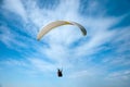 White paraglider flying in the blue sky against the background of clouds.