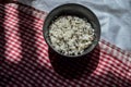 White parboiled black rice in dark cup on plate on a background of red-white cloth towels under the light of the sun with shadow Royalty Free Stock Photo