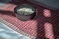 White parboiled black rice in dark cup on plate on red-white cloth towels under the light of the sun with shadow Royalty Free Stock Photo