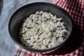 White parboiled black rice in dark cup on plate on red-white cloth towels under the light of the sun with shadow on table Royalty Free Stock Photo