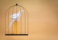 White parrot bird paper standing in black prison cage isolated on eco brown background with copy space. Royalty Free Stock Photo