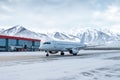 White passenger aircraft taxiing on the airport apron at winter on the background of high picturesque mountains