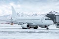 White passenger airliner at the jetway at winter airport apron on the background of high scenic mountains