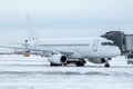 White passenger jetliner at the boarding bridge at winter airport apron