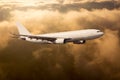 White passenger plane in flight. Aircraft fly high above the golden clouds during the sunset Royalty Free Stock Photo