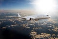 White passenger plane flies high above the clouds through the sun rays Royalty Free Stock Photo