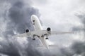 white passenger plane has released its landing gear and is landing against background of grey ominous clouds in heavy weather Royalty Free Stock Photo