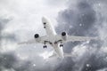 white passenger plane has released its landing gear and is landing through falling snow against background of grey ominous clouds