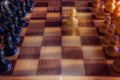 White pawn staying against full set of black chess pieces. Closeup of chessboard with wooden pieces on table in sunlight, game of Royalty Free Stock Photo