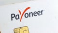 White Payoneer plastic card with logo and chip on light background close up