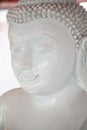 White peaceful Buddha statue meditating with closed eyes close-up. Religious stone sculpture at Buddhist shrine in Thailand