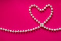 White pearl heart on a bright pink background. Pearl beads in th