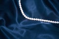 White pearl necklace on a dark blue silk Royalty Free Stock Photo