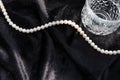 White pearls necklace and glass on black flannel. Royalty Free Stock Photo
