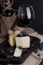 White pecorino cheese and blueberries. Traditional Italian hard cheese and a glass of red wine. Wooden background and dark style Royalty Free Stock Photo