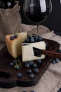 White pecorino cheese and blueberries. Traditional Italian hard cheese and a glass of red wine. Wooden background and dark style Royalty Free Stock Photo