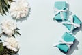 White peonies and turquoise gifts boxes on blue background. Beauty floral background, trendy shadows