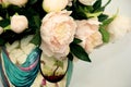 A white peony flower bouquet in a color vase on a white background